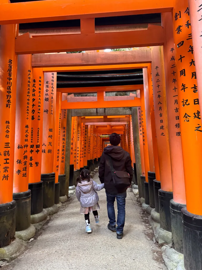 A parent and kid walking through Fushimi Inari Shrine