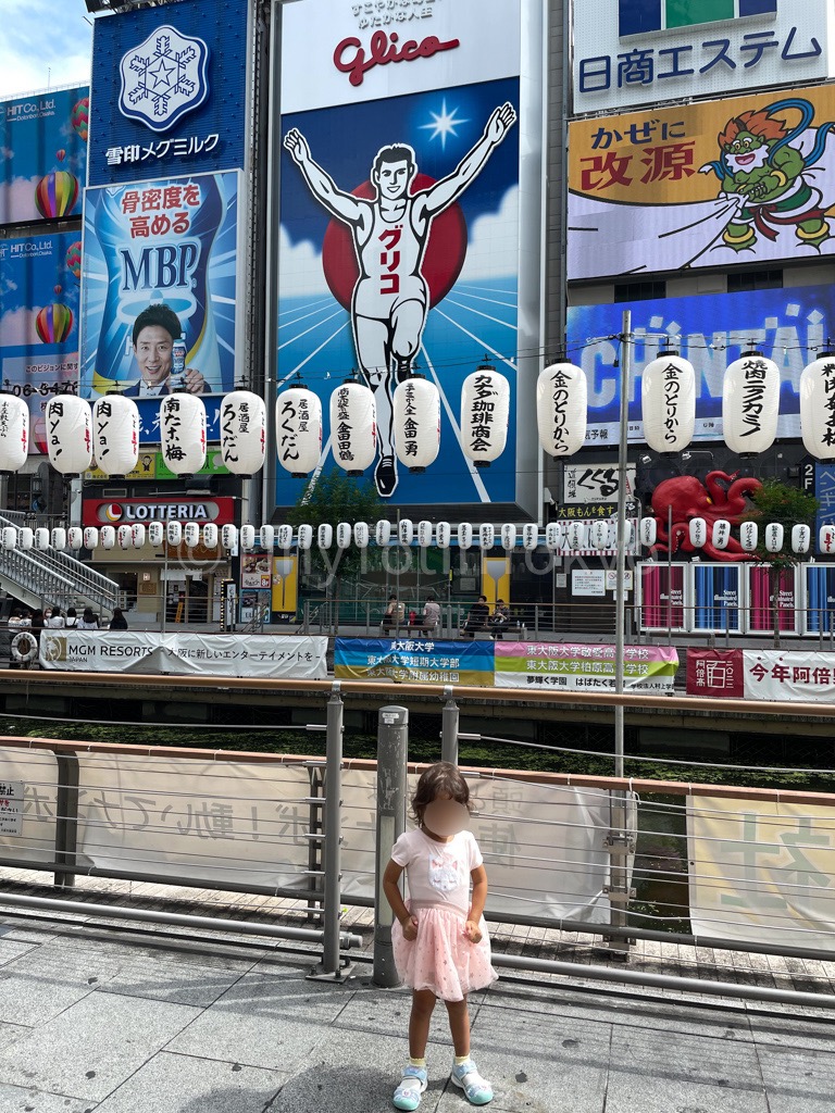 Girl standing in front of Glico sign in Dotonbori Osaka