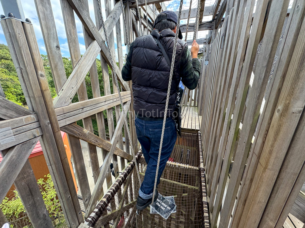 man doing difficult part of the maze involving walking on ropes at naruto theme park in Japan