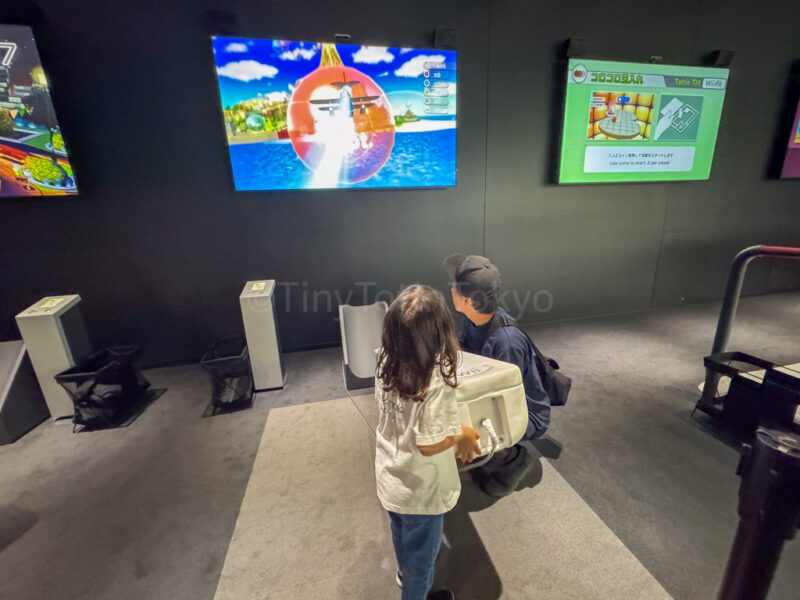 a child and parent playing the wii at the nintendo museum in kyoto