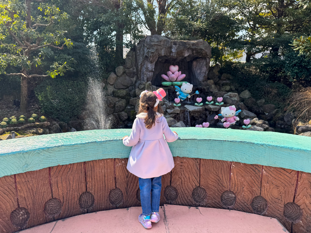 A girl standing in front of a Hello Kitty fountain at Harmonyland