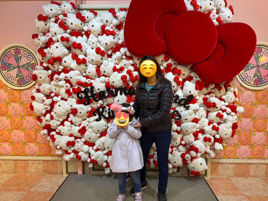 a mother and daughter standing in front of a hello kitty stuffie mural at Harmonyland