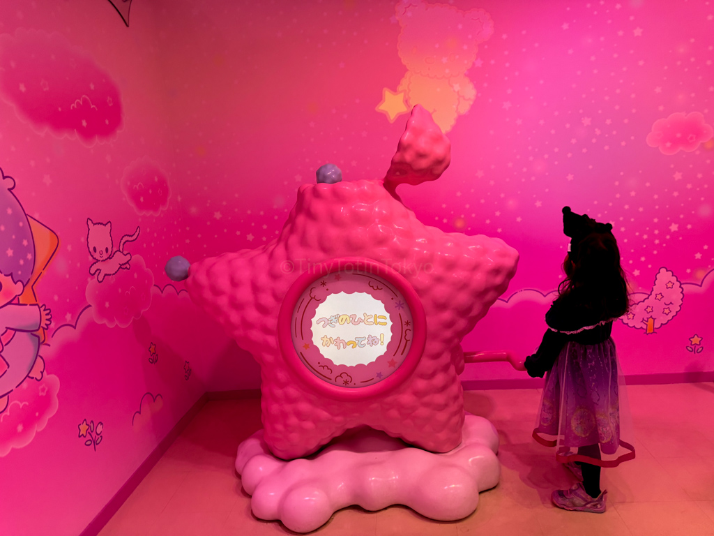 a girl turning the handle on a interactive star shaped item at Sanrio Puroland