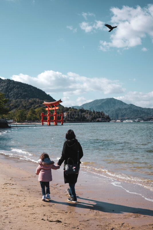 The author and their daughter walking to the Grand Torii Gate in Miyajima