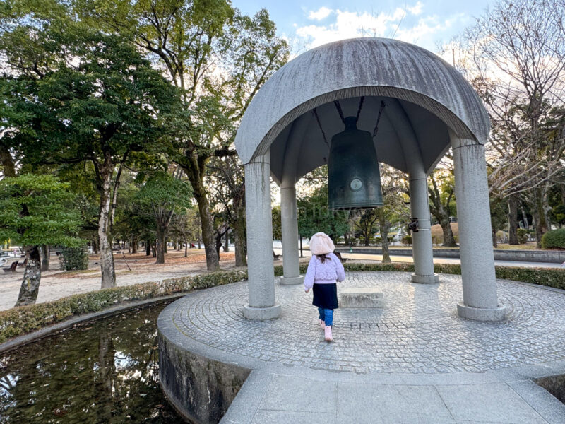 A child standing in front of the Bell of Peace in Hiroshima
