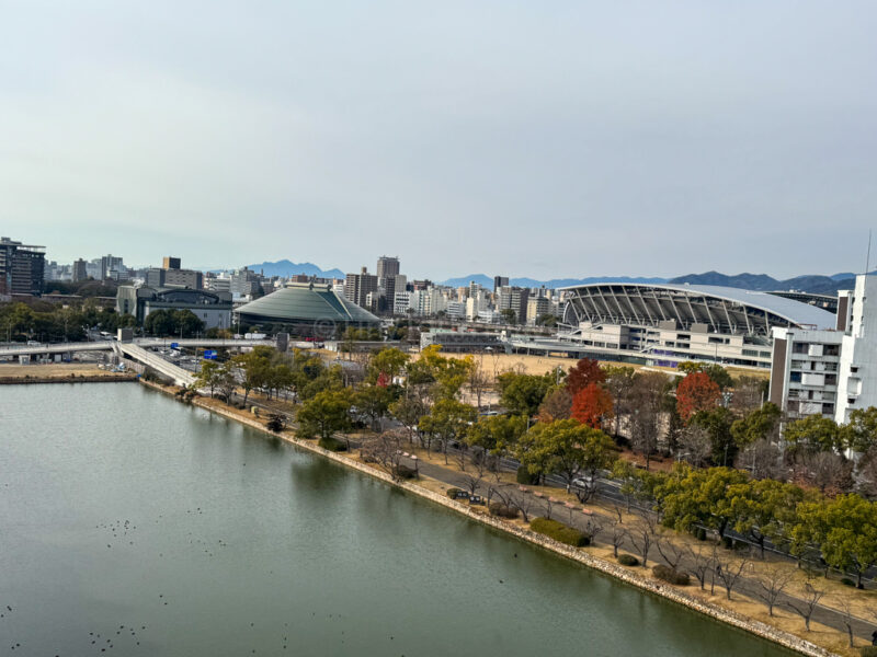 view from hiroshima castle showing a body of water with a hiroshima city in the background
