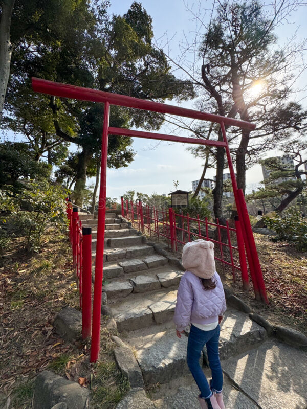 a girl standing on stairs with red torii gates at Shukkeien Garden in Hiroshima