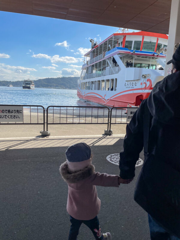 A child with their father boarding the ferry for Miyajima