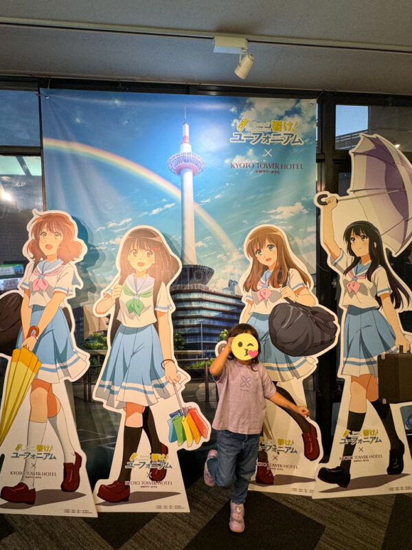 a child at Kyoto Tower posing with an anime Collab