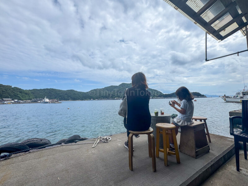 a mother and child sitting at a coffee house in ine kyoto by the sea