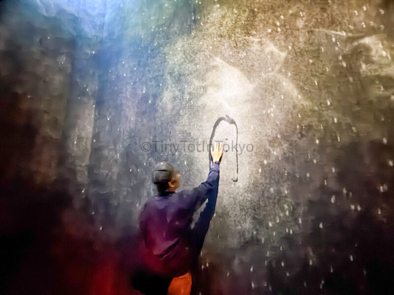 a man touching kanji at What a Loving and Beautiful World at teamlab kyoto