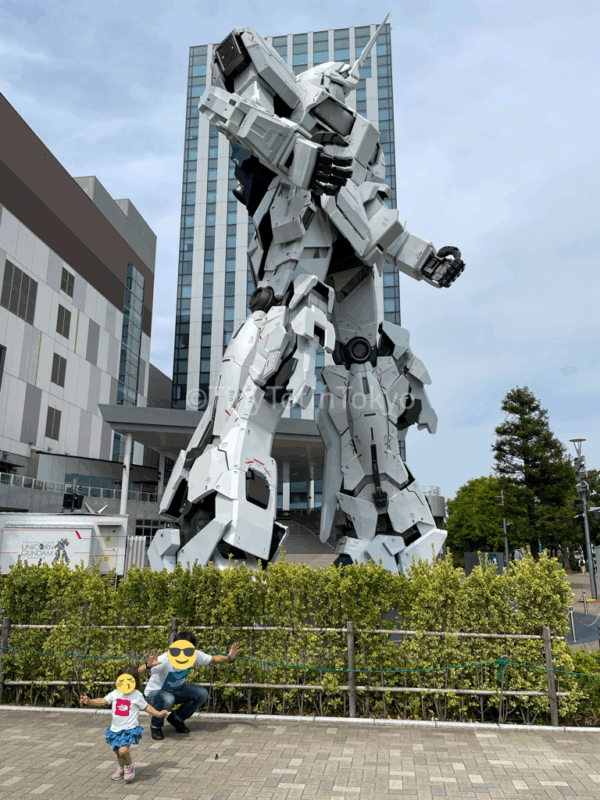 a child and father in front of the gundam statue
