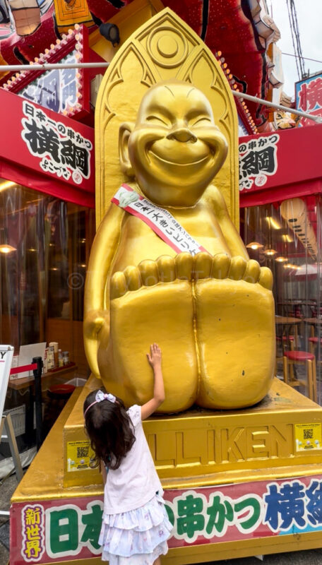 a child rubbing Biliken's feet