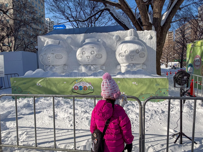 a child standing in front of Chiikawa sculptures at sapporo snow festival