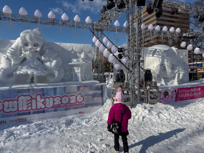 a child in front of Miku and Oshi no Ko snow sculptures at sapporo snow festival
