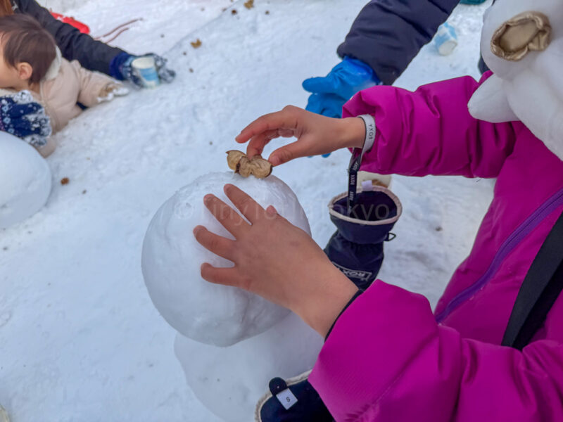 a child making a snowman at sapporo snow festival