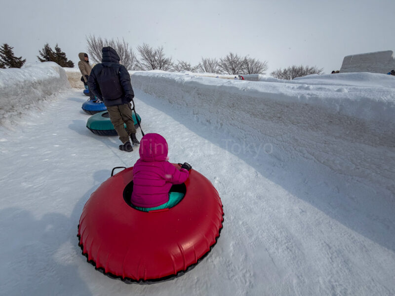 a child being pulled on a tube slider at sapporo snow festival 
