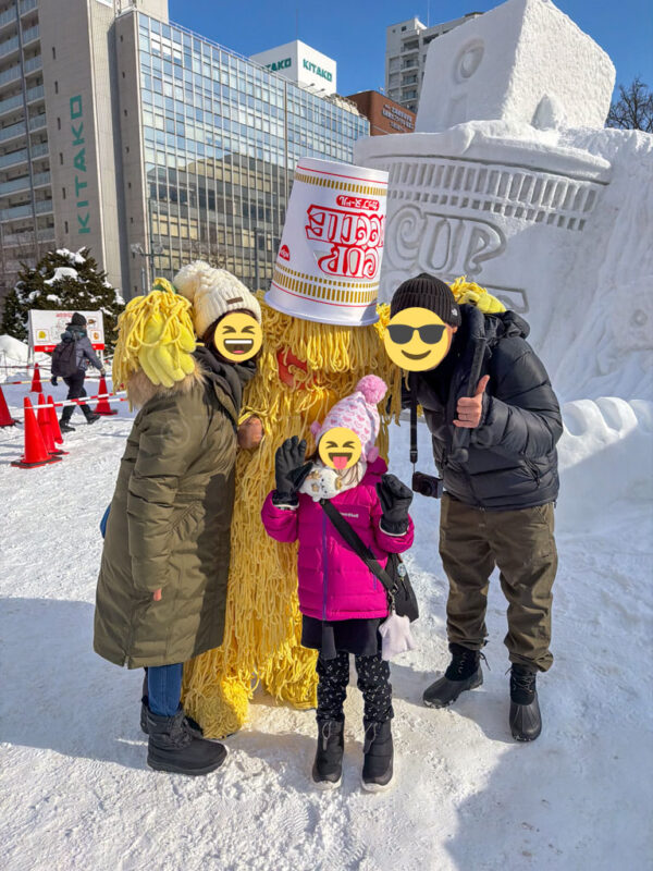 Family posing with cup noodles monster at sapporo snow festival.
