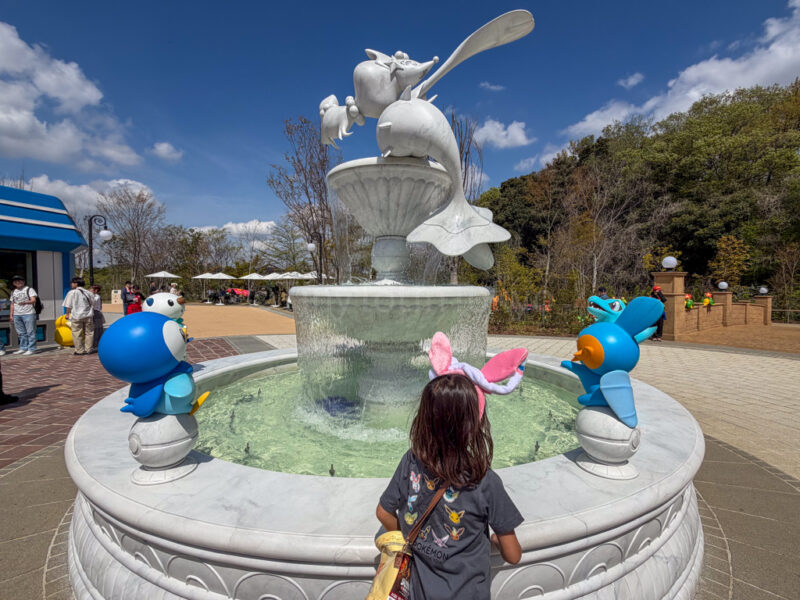 a child standing in front of a water fountain at pokepark kanto