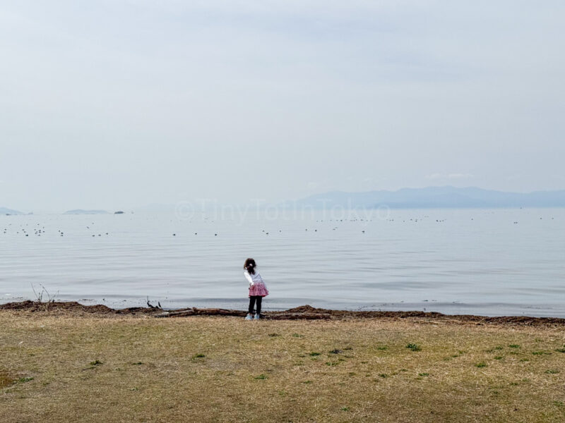 a child standing in front of Lake Biwa