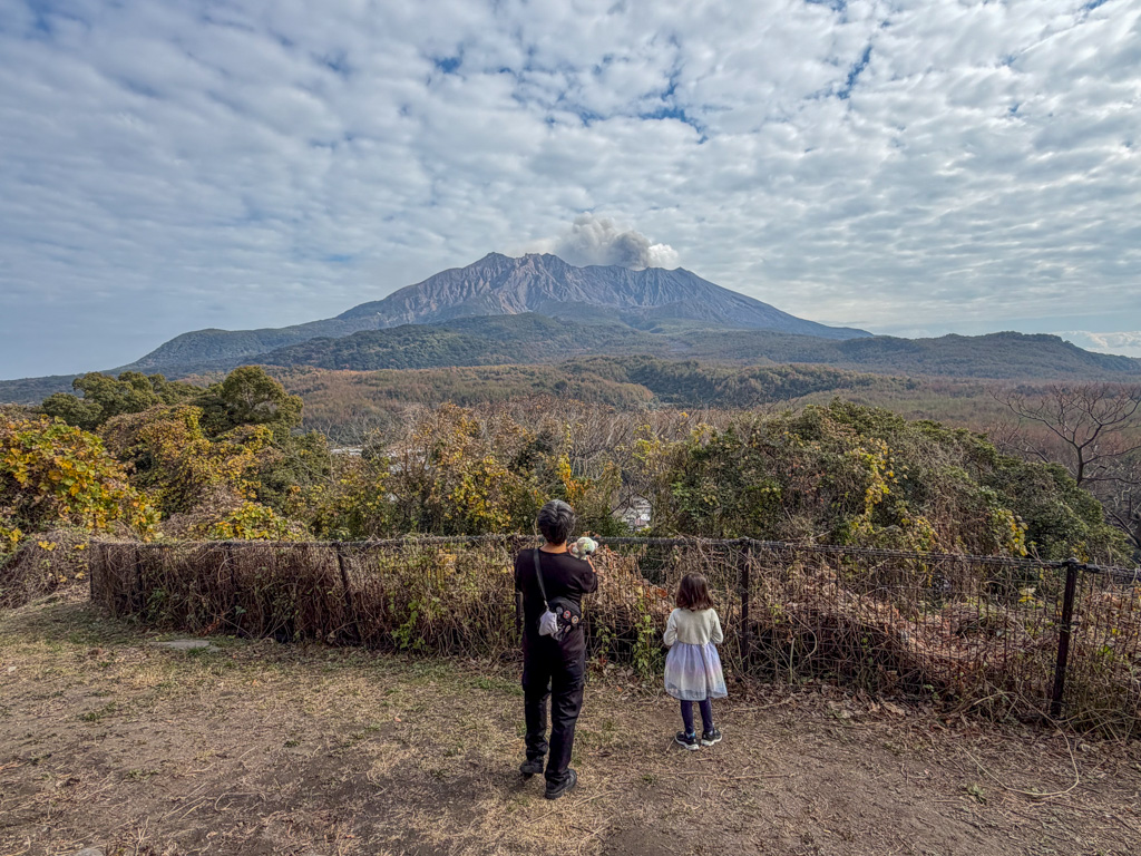 a parent and child in front of Sakurajima