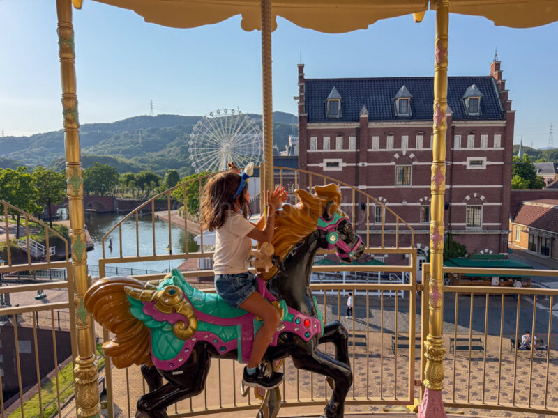 a child riding the sky carousel merry go round at huis ten bosch