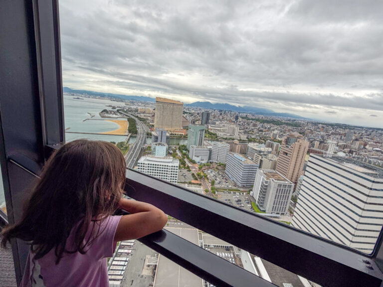 a child looking out at buildings and hotels in Fukuoka city